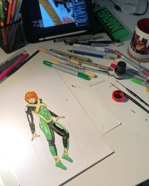 pic of my desk while drawing with a lot of copic markers and an iPad with a Jim Lee twich stream in the background